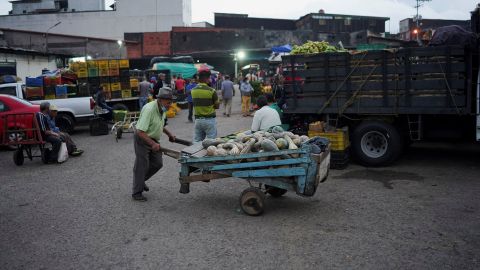 مردی گاری با کدو تنبل را به بیرون از بازار عمومی در سن کریستوبال، ونزوئلا، 7 آوریل 2022 هل می دهد.
