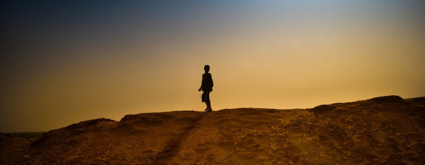 پسری روی یک ساحل شنی اطراف یک کمپ پناهندگان در M'bera، موریتانی راه می‌رود.